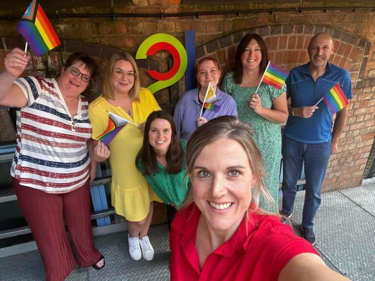 A photo of LSC team members smiling and holding Pride flags.