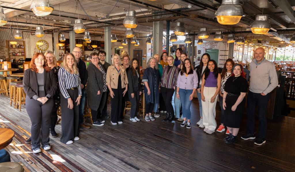 A photo of approximately 20 of the Learning Support Centre team standing in a semi-circle in a restaurant.