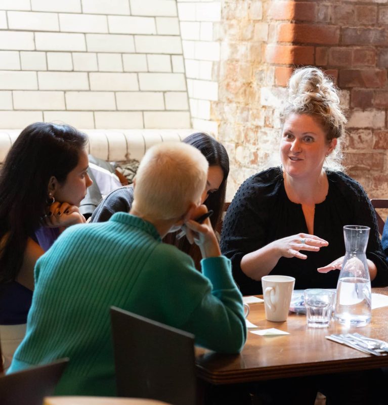 A group of women sitting around a table and talking.